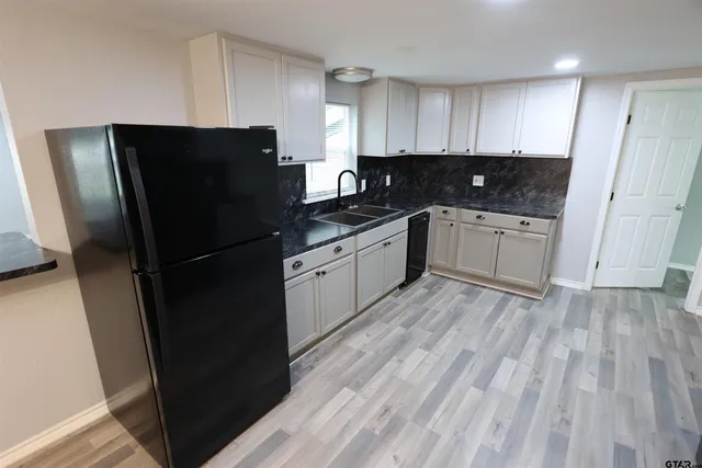 a kitchen with granite countertop stainless steel appliances refrigerator sink and cabinets