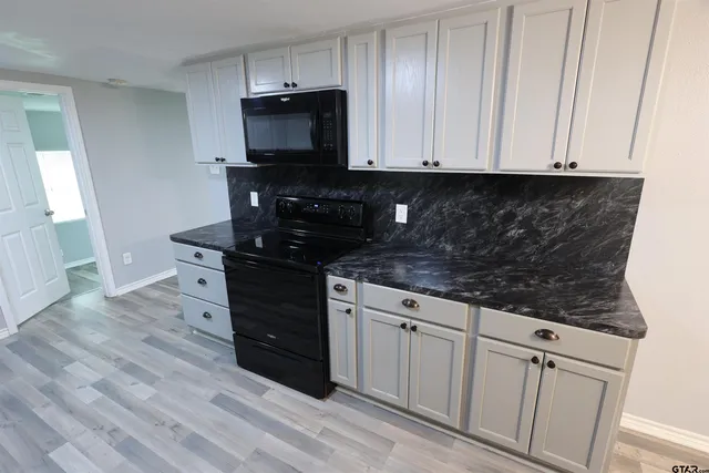 a kitchen with granite countertop white cabinets and black appliances