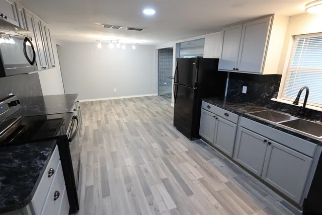 a kitchen with granite countertop a refrigerator stove and sink