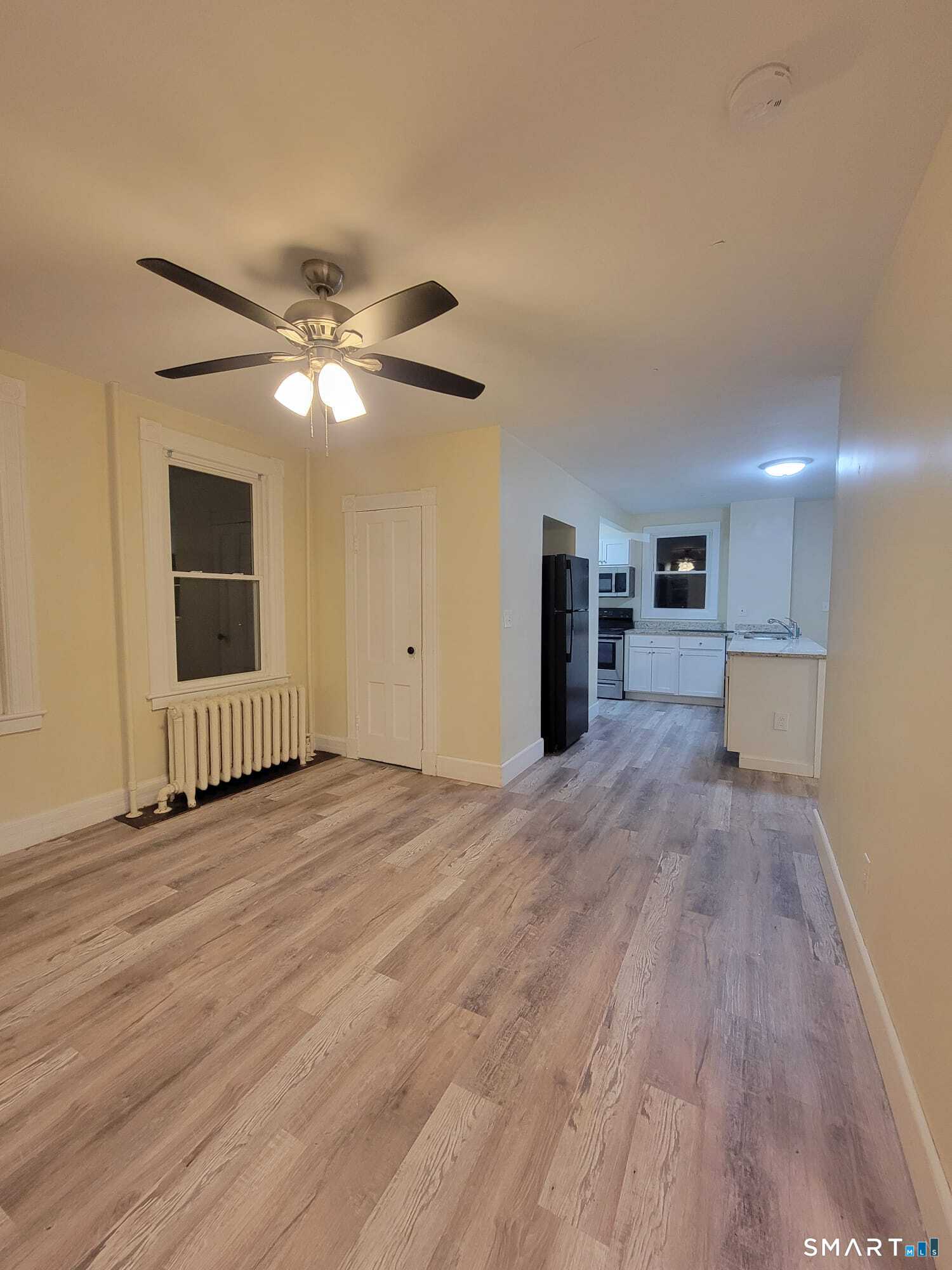 a view of a livingroom with a ceiling fan window and wooden floor