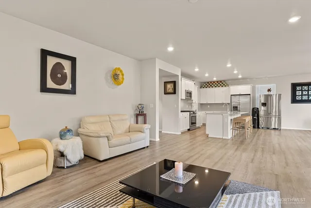 a living room with furniture and kitchen view with wooden floor