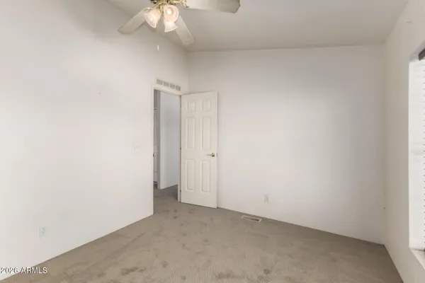 an empty room with a chandelier fan and closet