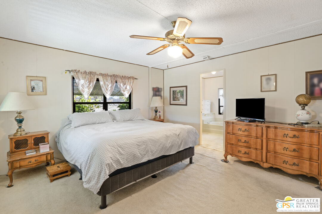 18555 Roberts Road, Unit 103 Desert Hot Springs, CA 92241 - Photo 14 of 30 a bedroom with a bed a dresser and painting on the wall