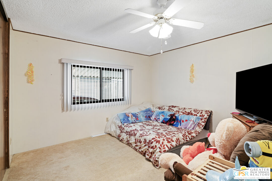18555 Roberts Road, Unit 103 Desert Hot Springs, CA 92241 - Photo 16 of 30 a bedroom with a bed and a chandelier