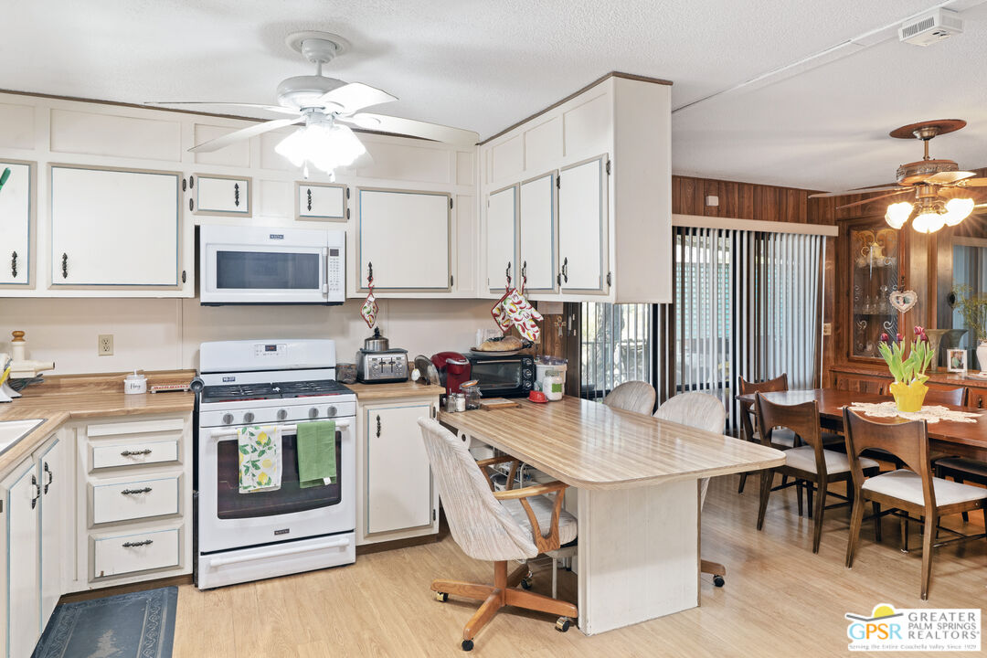 18555 Roberts Road, Unit 103 Desert Hot Springs, CA 92241 - Photo 2 of 30 a kitchen with stainless steel appliances a stove a sink dishwasher a refrigerator with a dining table and chairs with wooden floor