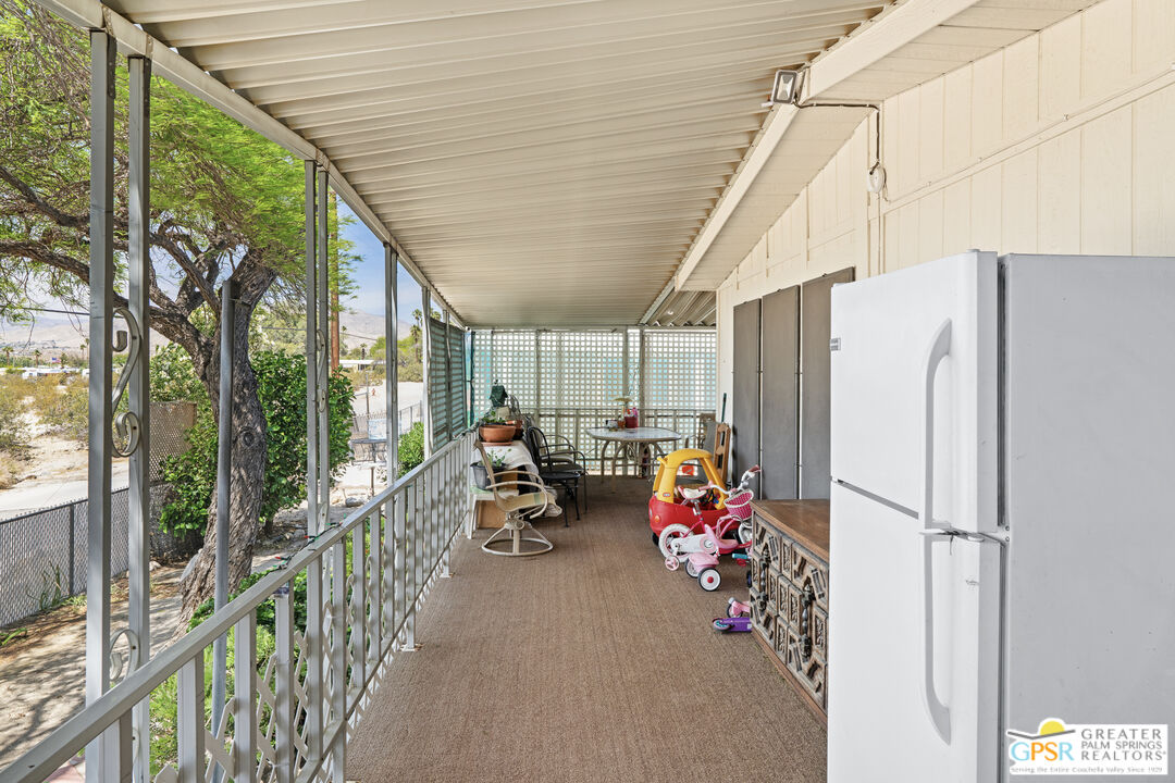 18555 Roberts Road, Unit 103 Desert Hot Springs, CA 92241 - Photo 21 of 30 a view of a patio with table and chairs and couches with wooden floor and fence