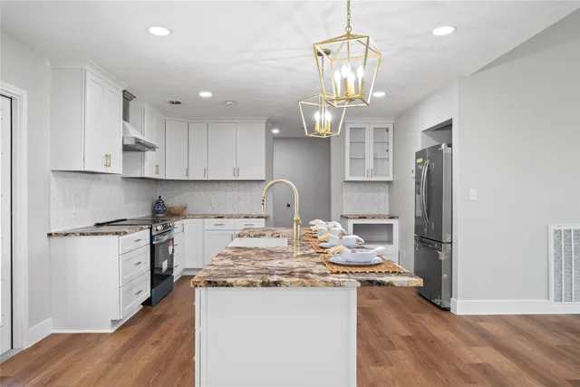 an open kitchen with wooden floor and stainless steel appliances