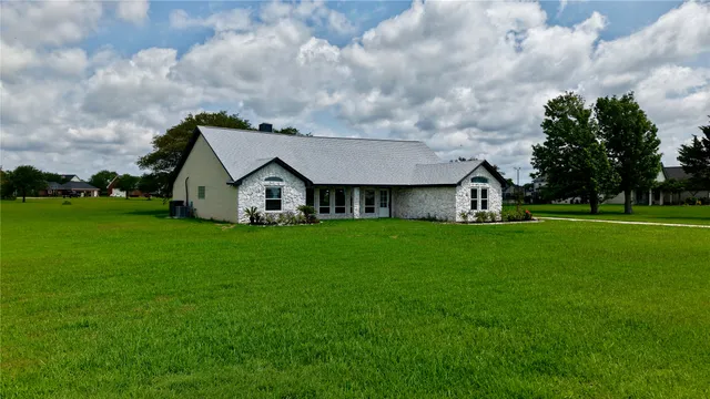a view of a house with a big yard and large trees