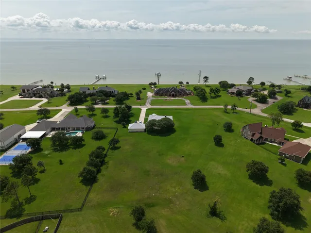 a view of a table and chairs under an umbrella in big yard with large trees