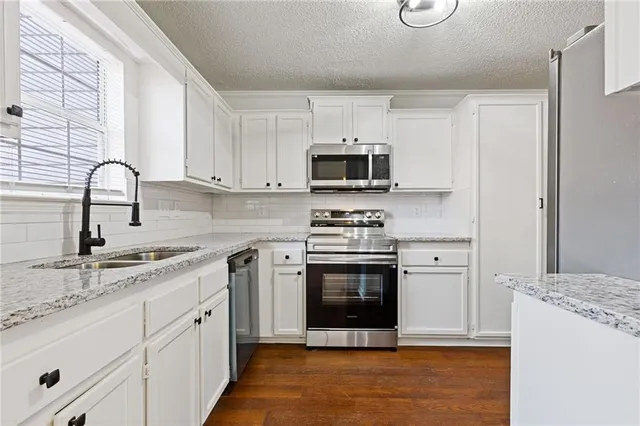 a kitchen with stainless steel appliances granite countertop white cabinets and a stove a oven with white countertops