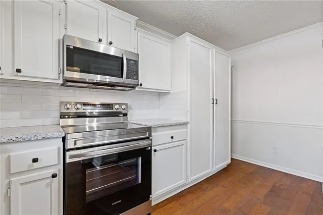 a kitchen with granite countertop white cabinets and white appliances