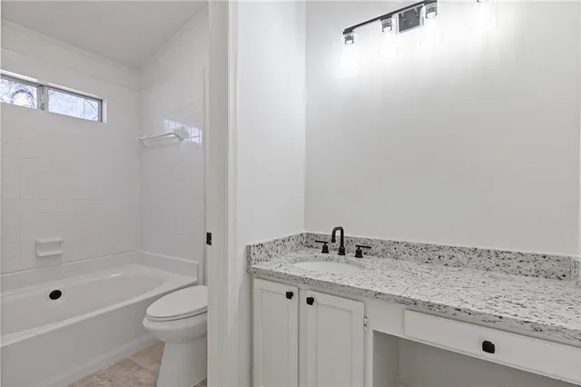 a bathroom with a granite countertop sink a toilet and shower