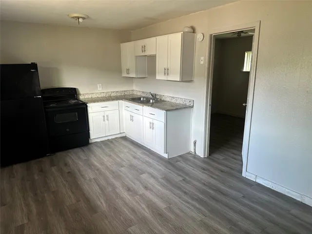 a kitchen with granite countertop white cabinets and black appliances