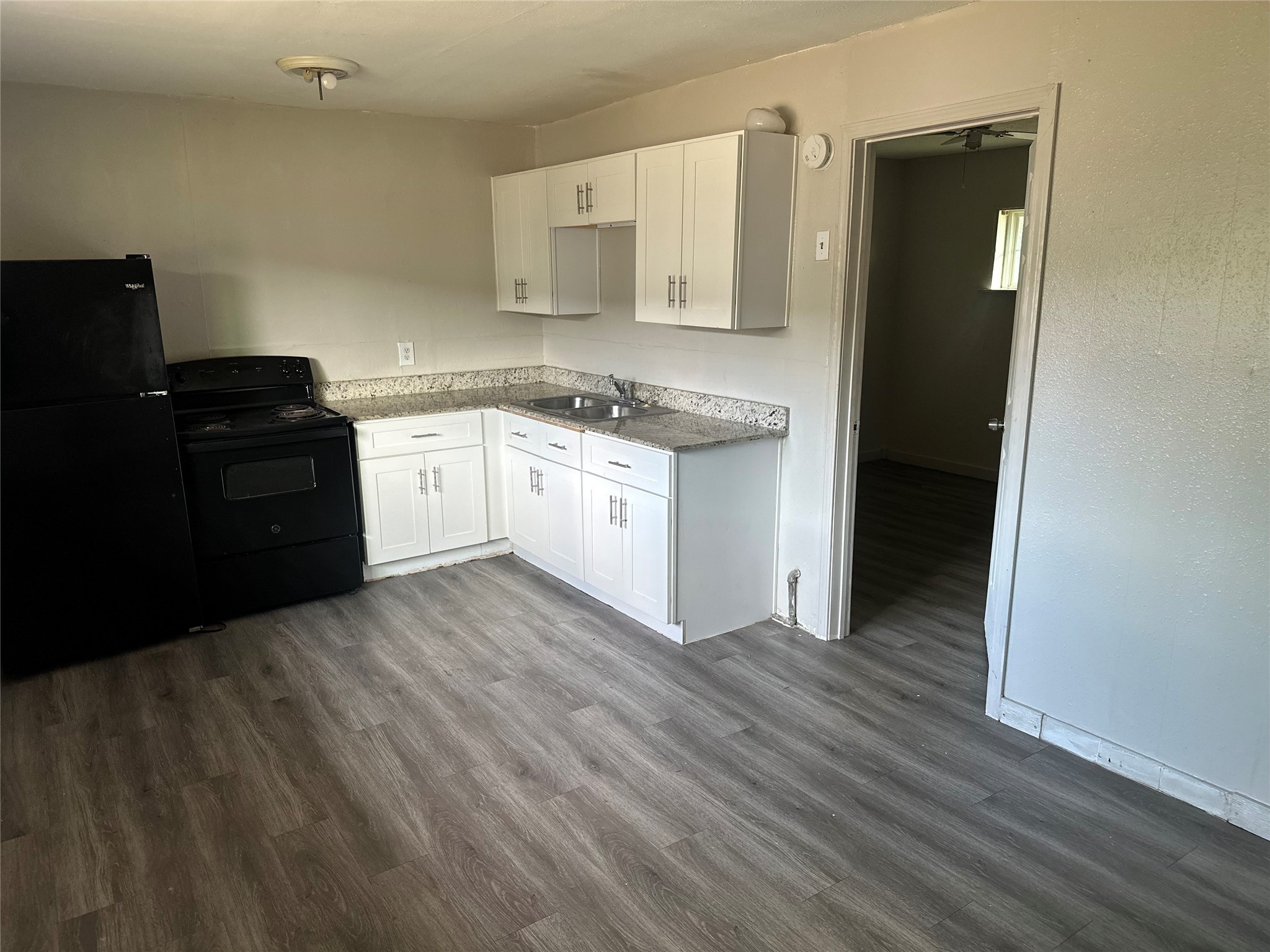 a kitchen with granite countertop white cabinets and black appliances