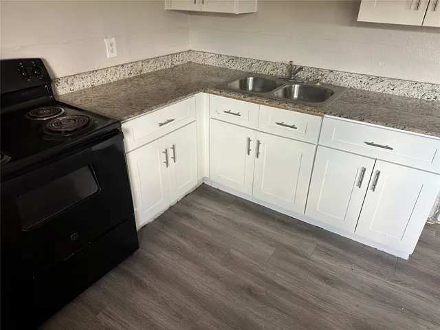 a kitchen with granite countertop white cabinets and a stove