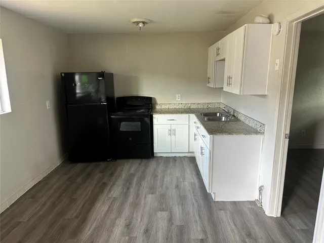 a kitchen with a refrigerator stove and wooden floor