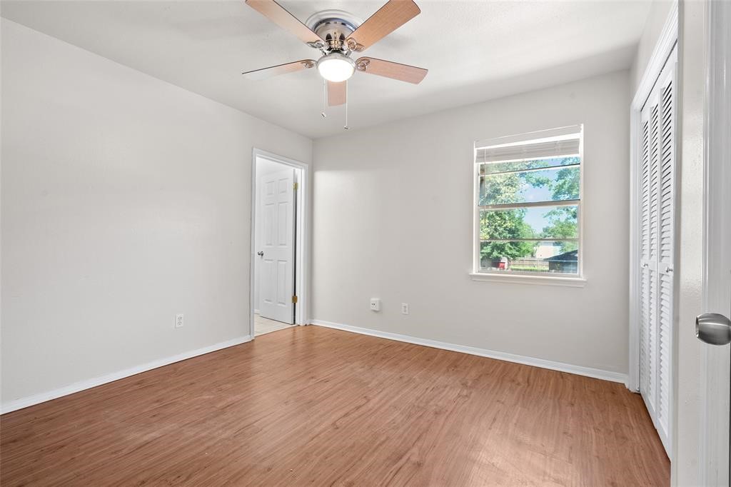 328 South 2nd Street, Unit 330 Alvin, TX 77511 - Photo 11 of 15 an empty room with wooden floor chandelier fan and windows