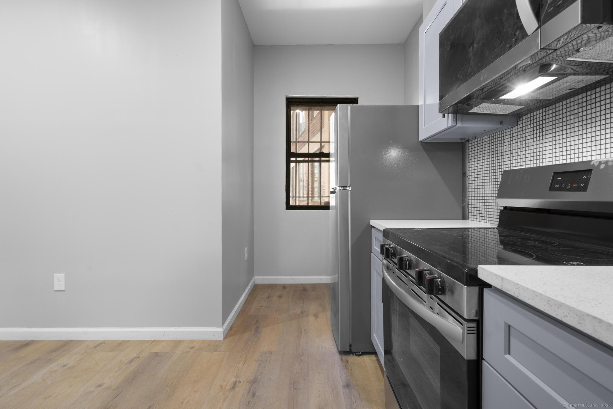 140 Grand Street, Unit 2C Waterbury, CT 06702 - Photo 8 of 13 a kitchen with granite countertop a stove and a microwave