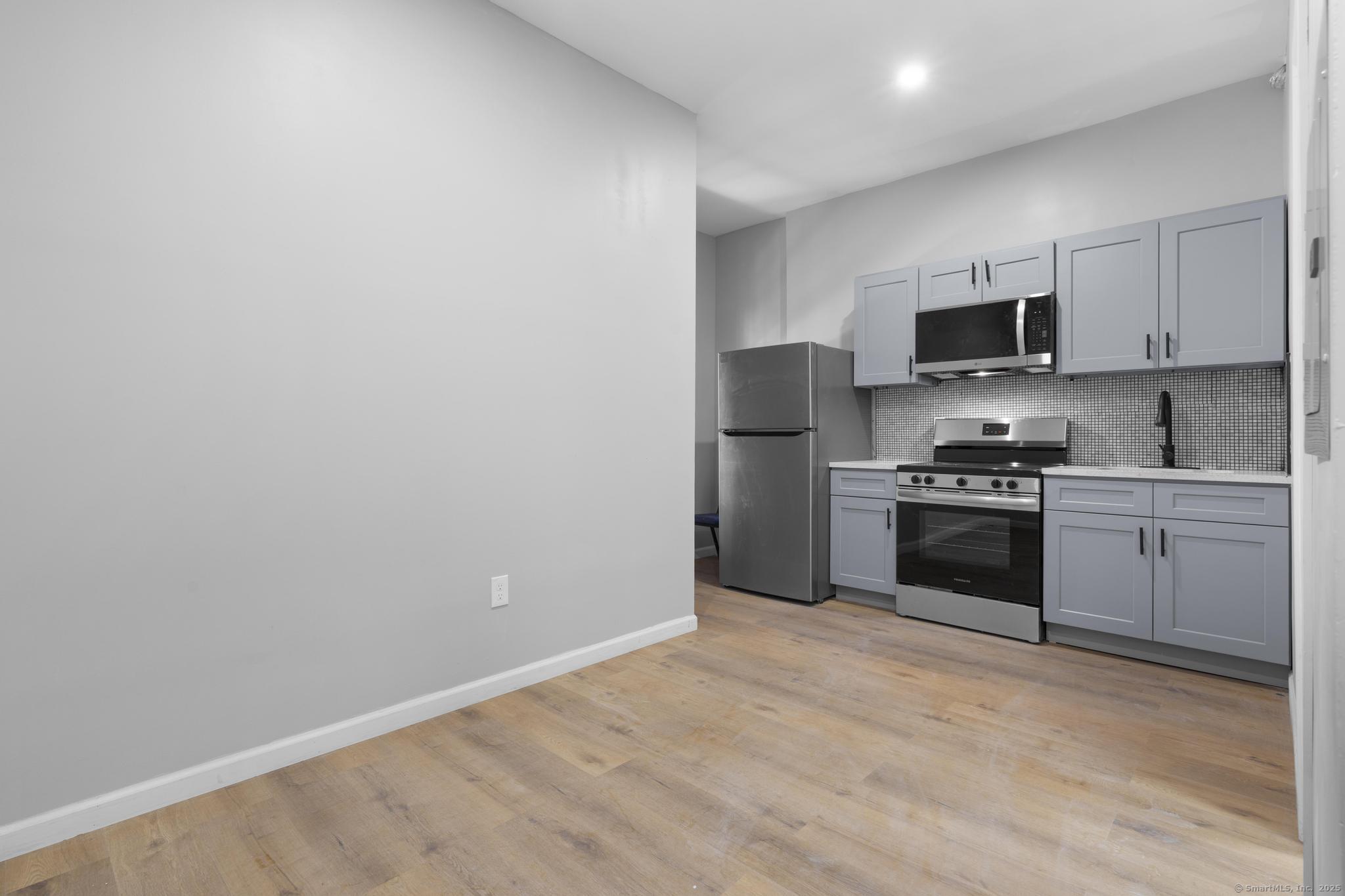 140 Grand Street, Unit 2C Waterbury, CT 06702 - Photo 9 of 13 a kitchen with granite countertop a refrigerator stove and microwave