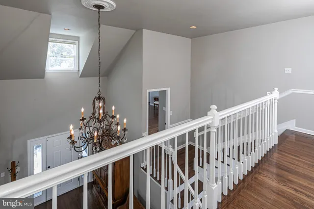 a view of a hallway with wooden floor and chandelier