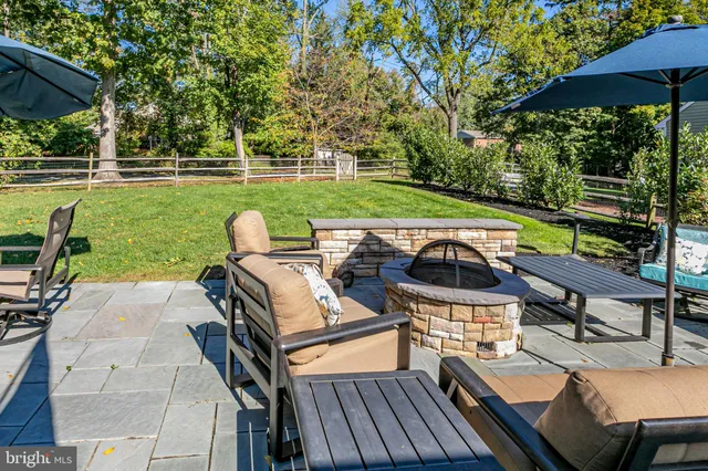 a view of a patio with table and chairs under an umbrella with wooden floor and fence