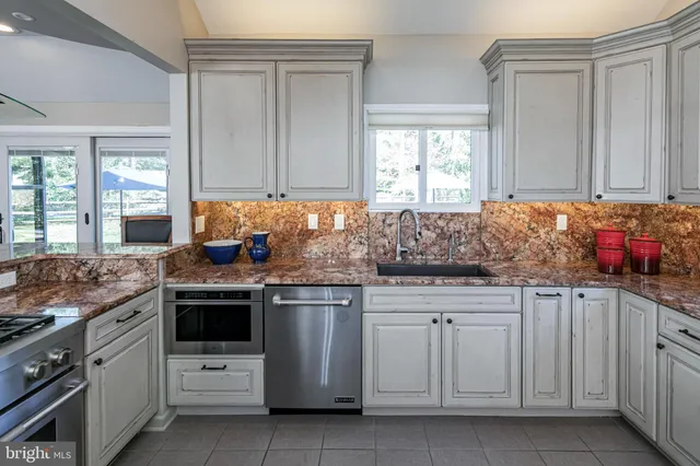 a kitchen with granite countertop white cabinets sink and stainless steel appliances