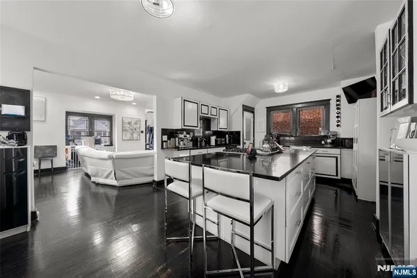 a kitchen with stainless steel appliances kitchen island granite countertop a stove top oven a sink a dining table and chairs with wooden floor