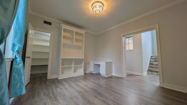 an empty room with wooden floor closet and windows
