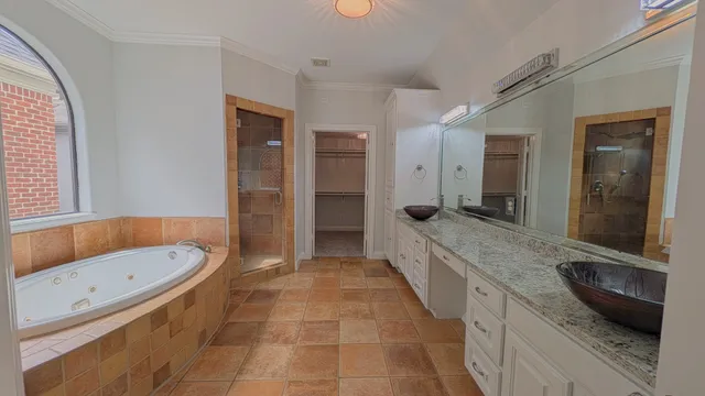 a bathroom with a granite countertop tub a double vanity sink and a large mirror