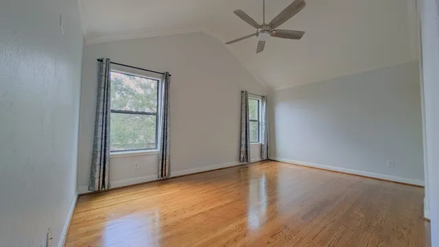 a view of an empty room with a window and wooden floor