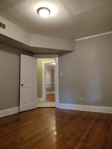 a view of an empty room with wooden floor and closet