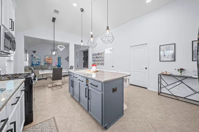 a large kitchen with stainless steel appliances kitchen island granite countertop a stove a sink a oven and a white cabinets