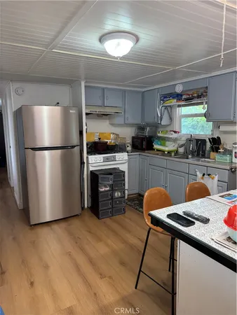 a kitchen with stainless steel appliances a refrigerator a sink a stove a table and chairs