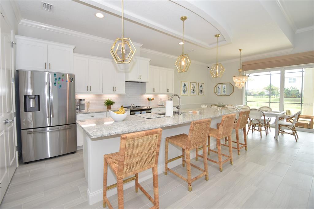 114 Del Palma Drive Palm Coast, FL 32137 - Photo 6 of 63 a kitchen with granite countertop a refrigerator a stove a dining table and chairs with wooden floor
