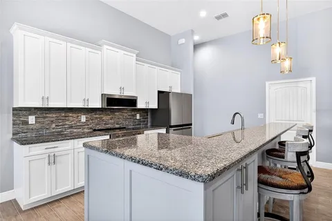 a kitchen with granite countertop a sink a stove and cabinets