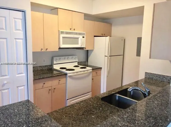 a kitchen with a refrigerator sink and cabinets