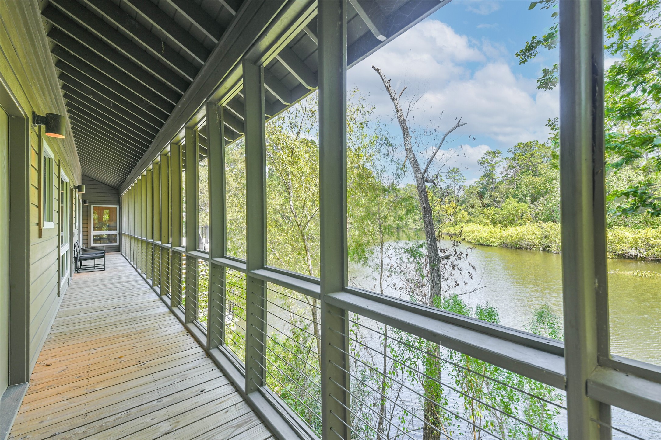 88 Raccoon Ramble Cleveland, TX 77327 - Photo 25 of 43 Enjoy serene views of lush greenery and a tranquil river from this expansive screened-in porch, perfect for relaxation and outdoor enjoyment.