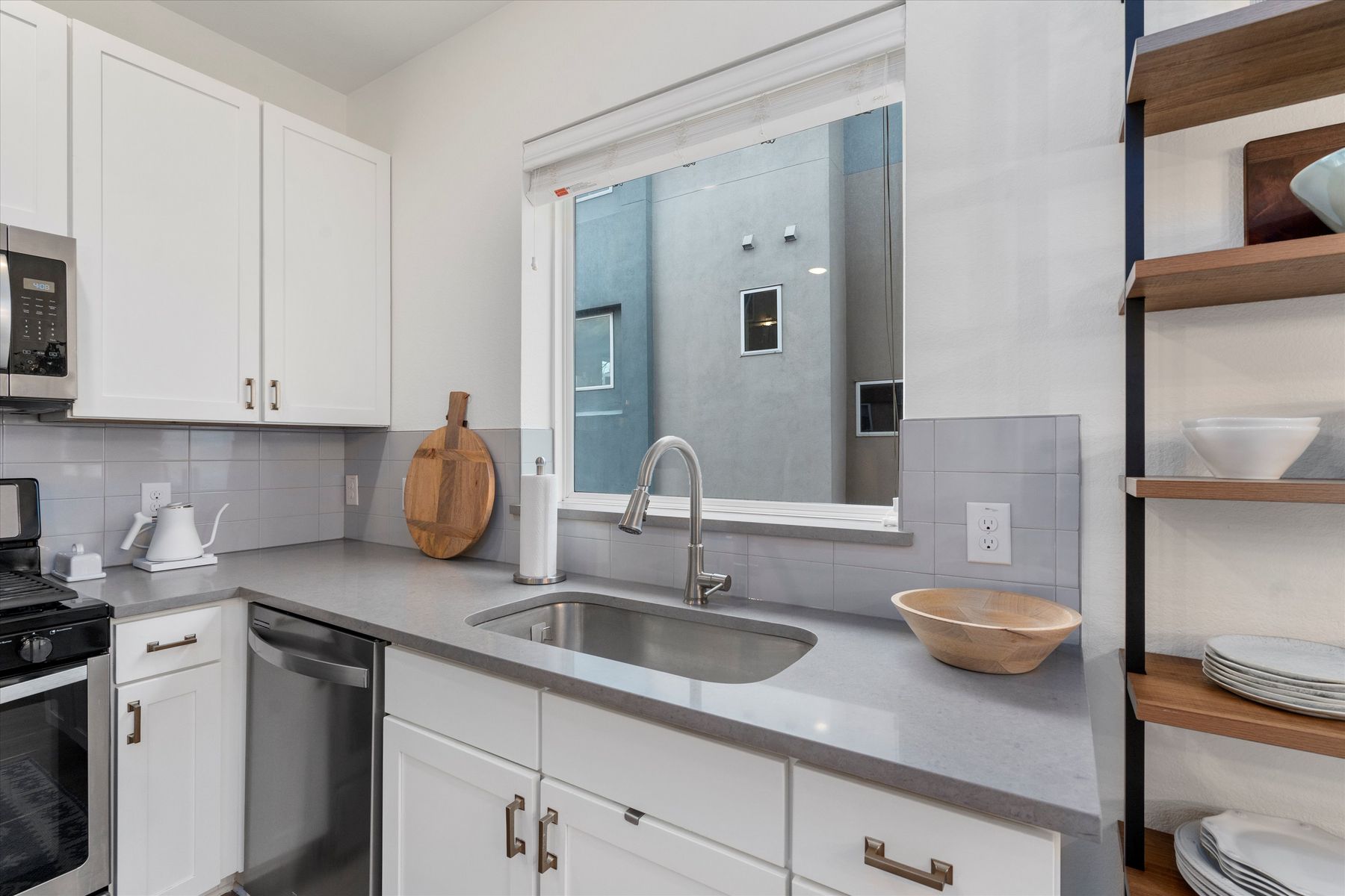 2827 Manor Road, Unit 3102 Austin, TX 78722 - Photo 7 of 18 A contemporary kitchen features bright white cabinetry, sleek countertops, and an integrated stainless steel sink with modern fixtures.