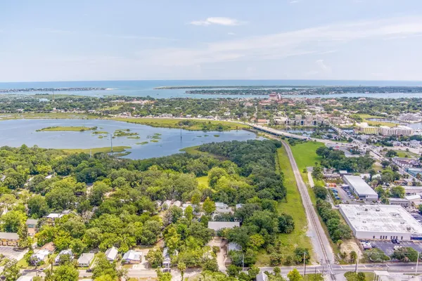an aerial view of ocean and residential houses with outdoor space