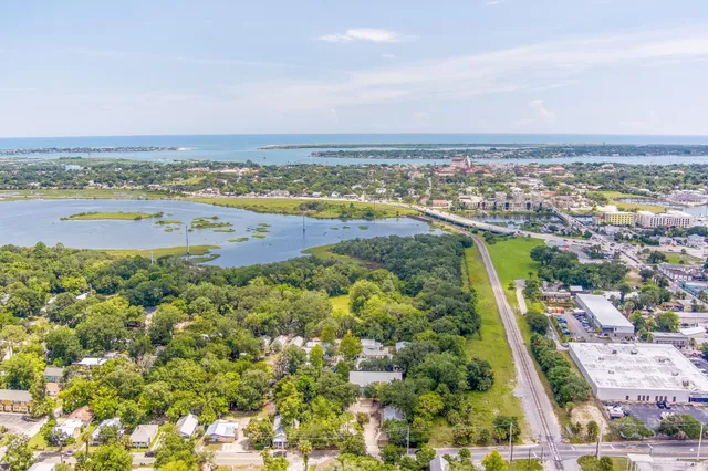 an aerial view of ocean and residential houses with outdoor space