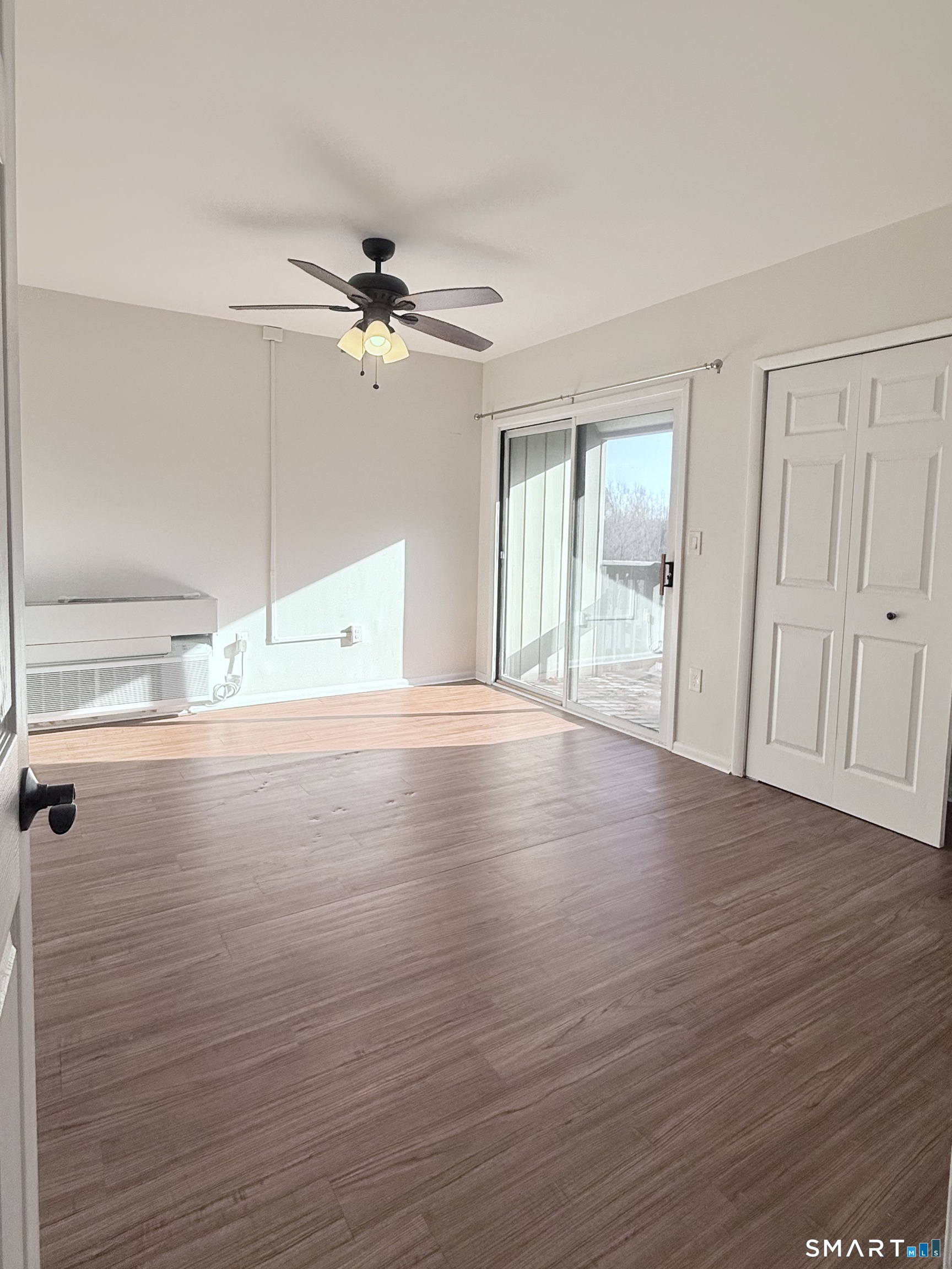 175 Mill Pond Road, Unit 106 Hamden, CT 06514 - Photo 13 of 22 an empty room with wooden floor fan and windows