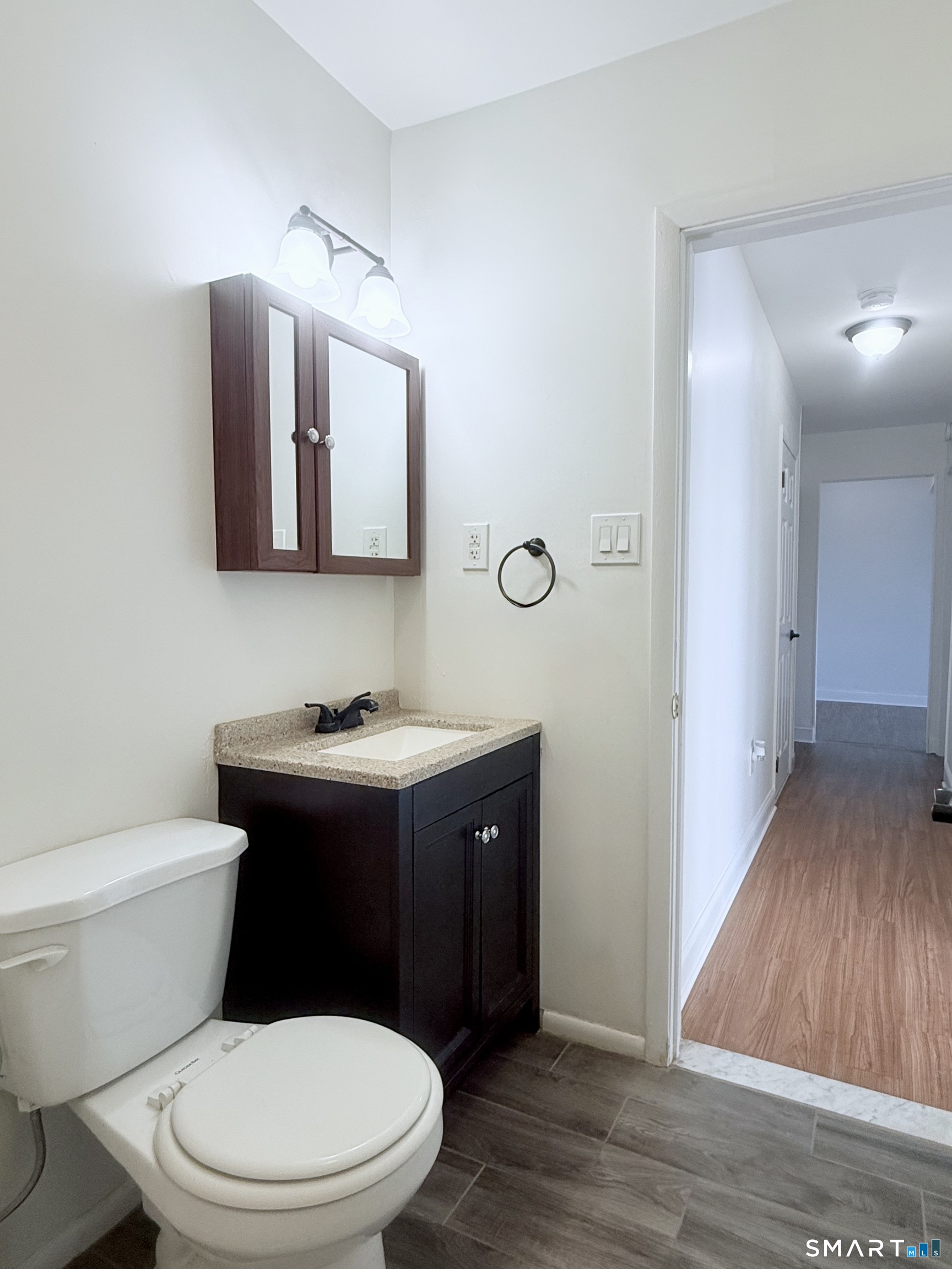 175 Mill Pond Road, Unit 106 Hamden, CT 06514 - Photo 17 of 22 a bathroom with a toilet sink vanity and mirror