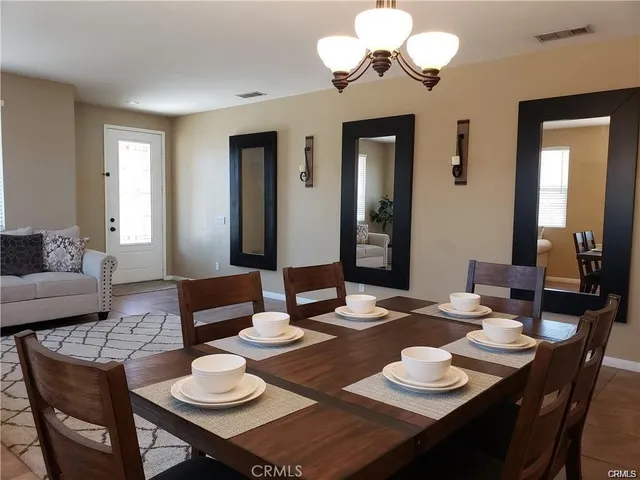 a dining room with wooden floor a chandelier a wooden table and chairs