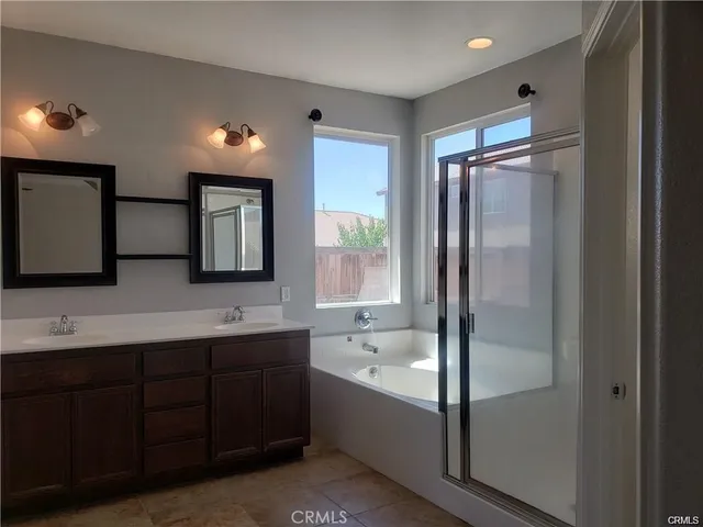 a bathroom with a double vanity sink mirror and bathtub