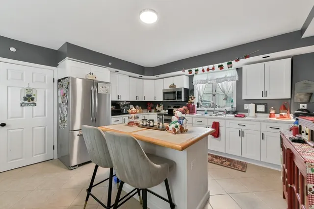 a kitchen with stainless steel appliances a sink a stove a refrigerator cabinets and dining table