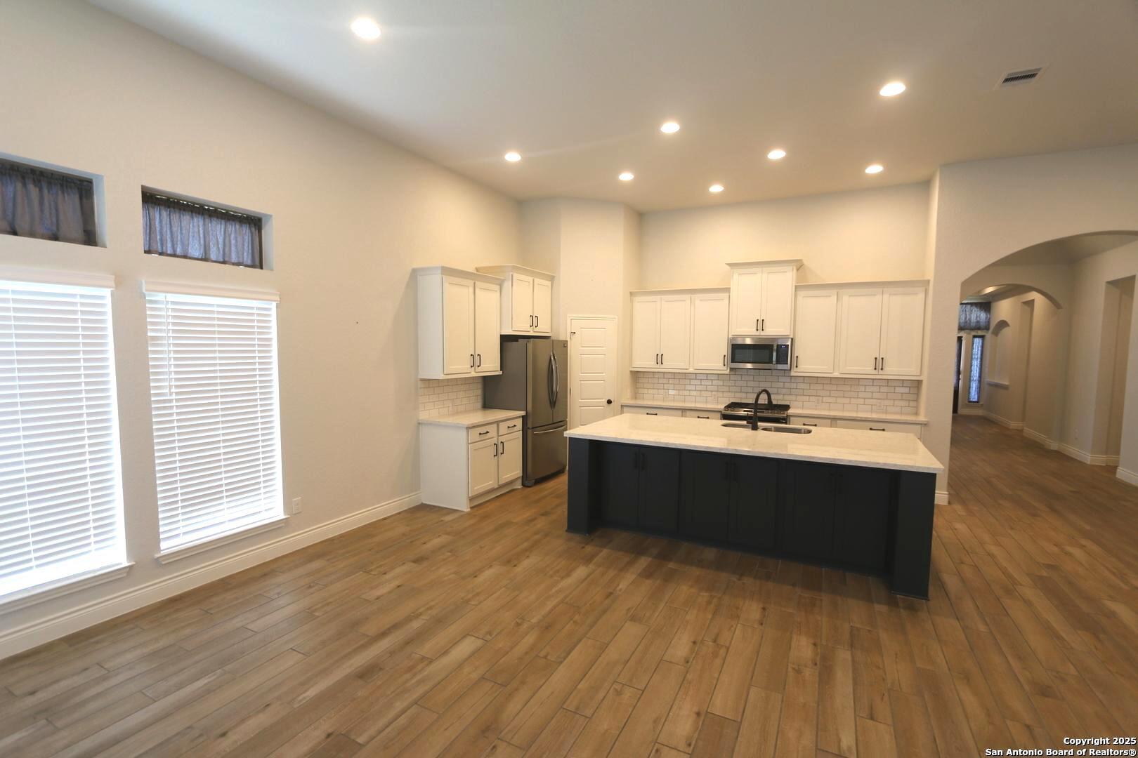 2965 Grove Way Seguin, TX 78155 - Photo 11 of 60 a large kitchen with stainless steel appliances granite countertop a lot of counter space and wooden floors