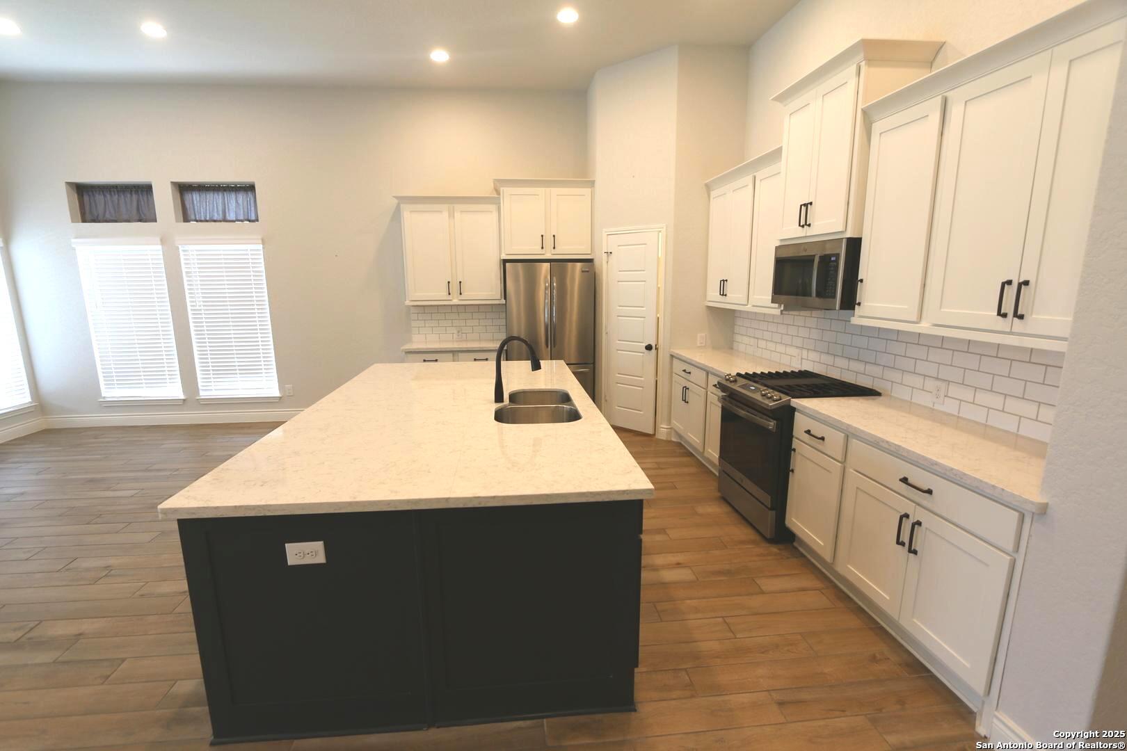 2965 Grove Way Seguin, TX 78155 - Photo 14 of 60 a large kitchen with stainless steel appliances kitchen island granite countertop a sink a stove counter space and cabinets