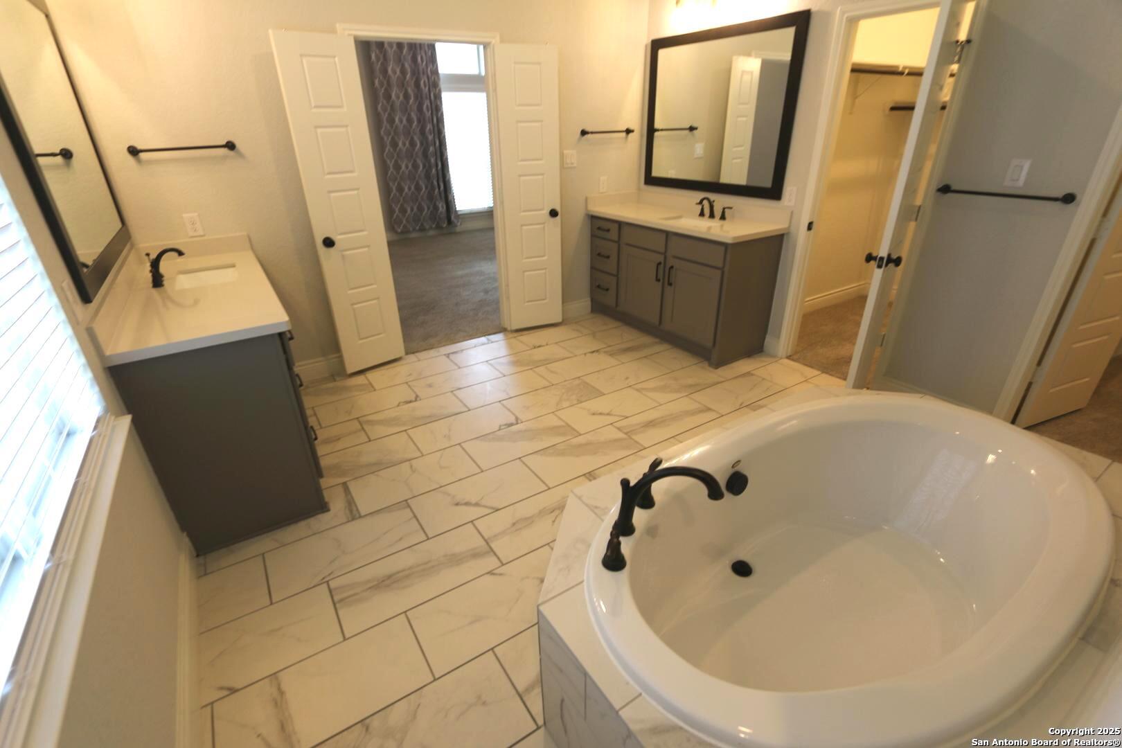 2965 Grove Way Seguin, TX 78155 - Photo 24 of 60 a bathroom with a tub a sink and a mirror