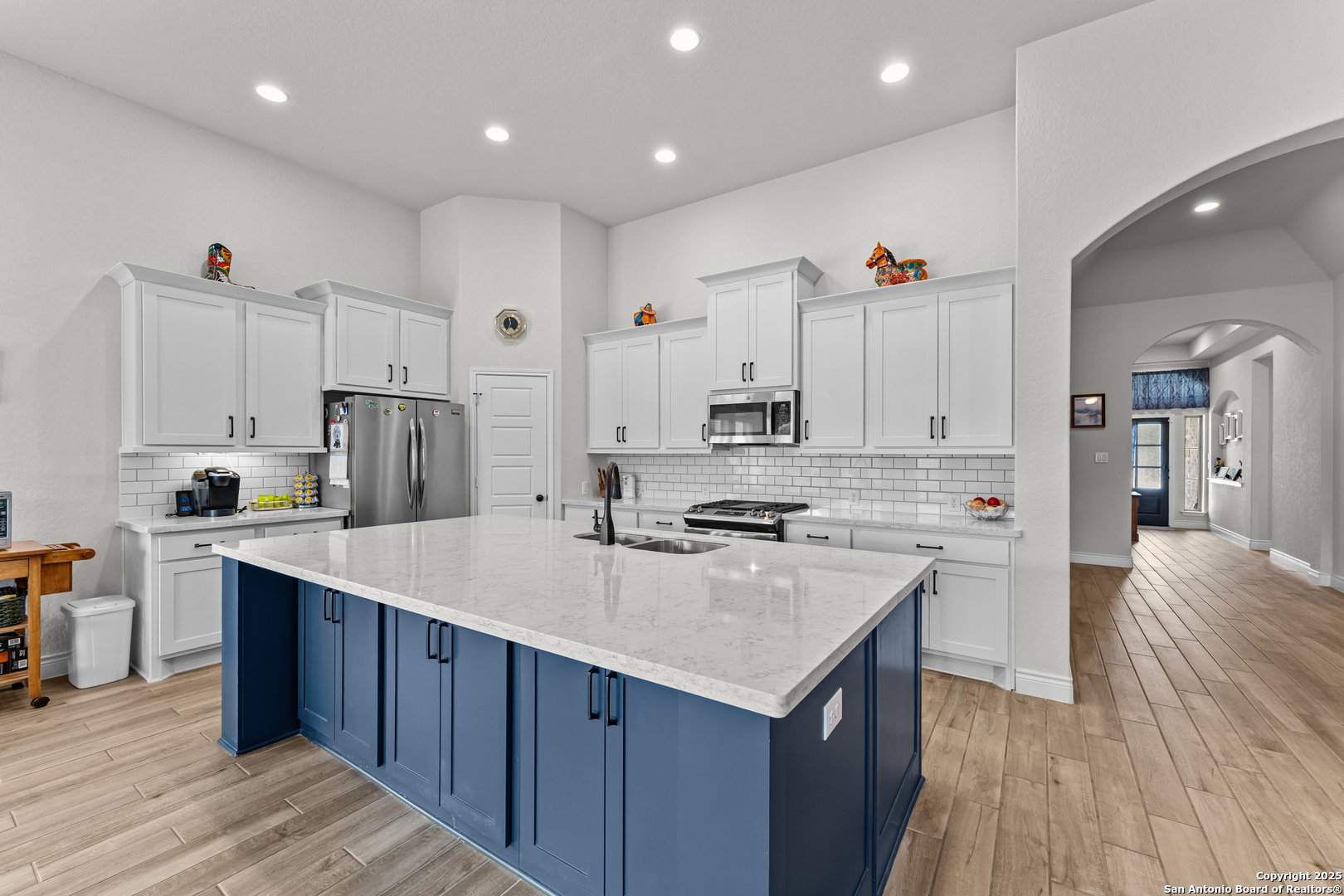 2965 Grove Way Seguin, TX 78155 - Photo 40 of 60 a kitchen with kitchen island a sink a stove a refrigerator and white cabinets with wooden floor