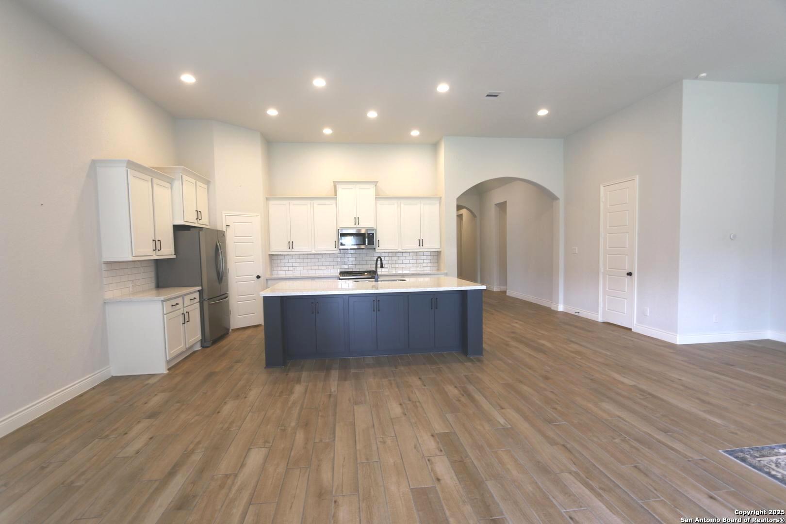 2965 Grove Way Seguin, TX 78155 - Photo 10 of 60 a large kitchen with stainless steel appliances a large counter top a sink dishwasher and a refrigerator with wooden floor